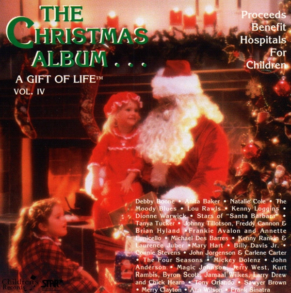 Album Cover "The Christmas Album A Gift Of Life." A cheery image of Santa Clause sitting in front of a fireplace, next to a fully decorated Christmas tree. He looks to a small child in his lap while another child stands near.